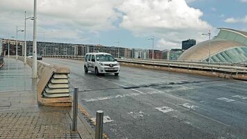 valência, Espanha 19.09.2023 molhado ponte cruzando dentro valência, Espanha, carros viagem através uma molhado ponte em uma nublado dia dentro valência, com distintivo arquitetura dentro a distância. video