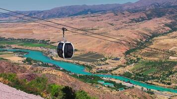 The drone flies over the cabins of a mountain funicular. Sunny summer day. There are green hills all around. video