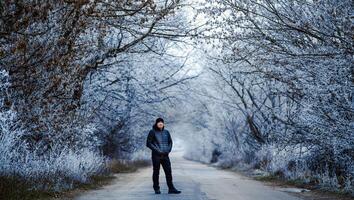 handsome smiling young man posing in winter park. Season of the year. Snow covered trees. photo