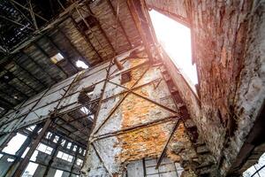 Abandoned industrial interior of the factory without windows and many holes on the background of the ceiling. Old ruined factory inside photo