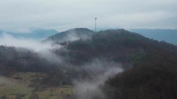 aéreo cerca orbital ver de brumoso y nublado colinas y radio torre en Eslovaquia video