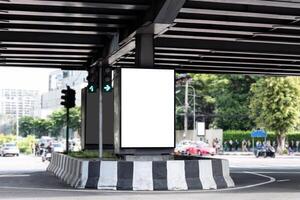 Outdoor vertical LED display billboard on crossroad with mock up white screen. Clipping path for mockup photo