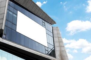 Mock up white horizontal billboard on mirror wall building with blue sky background .clipping path for mockup photo