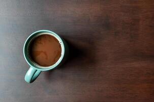 Top view mocha coffee in green cup on wooden table with copy space photo