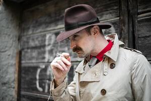 Vintage detective smoking a sigarette ina city slum photo