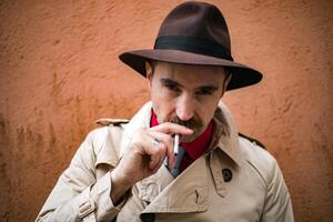 Vintage detective smoking a sigarette in a city slum photo