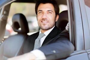 Portrait of an handsome smiling business man driving his car photo