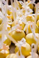 Delicious cake pops nicely decorated for an elegant wedding reception. Yellow cake pops on a tray for party. Close-up photo