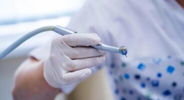 Stomatological instrument in dentists clinic. Doctor holding hand drill. Selective focus close up. photo