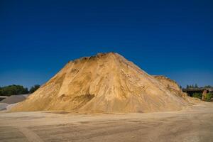 Sand slagheap for industrial needs. Blue sky background. Selective focus. photo