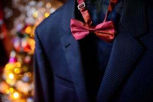 Dark blue wedding suit and wine-colored bow-tie on blurred background. Butterfly necktie on the man's costume. Close-up photo