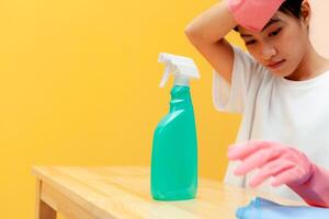 asian woman cleaning holding cleaning equipment Yellow background. housewife holding cleaning equipment. photo