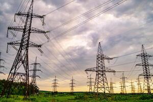 Electricity pylons and high-voltage power lines on the green grass. Power plant. Electrical power grid. View from below. photo