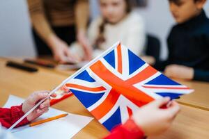 Kid's hands are holding England UK Flag. Studing foreign languages. English lesson. Closeup. photo