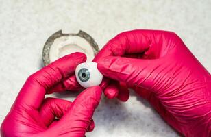 Ophthalmologist or surgeon holds in hand dressed in a blue glove eye photo