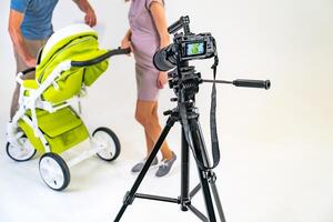 camera is on a tripod and focused on a young family with a stroller on a white background photo