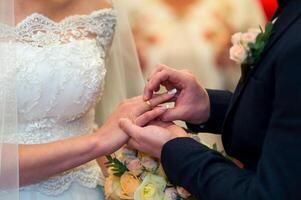 Groom putting a wedding ring on bride's finger. Wedding day. Closeup photo
