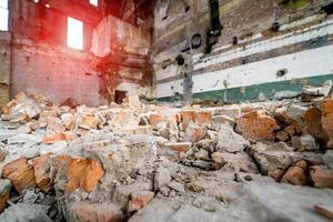 Remains of the destroyed industrial building inside. Large destroyed building with concrete pilings and scattered bricks with rebar against the frame of an old building. photo