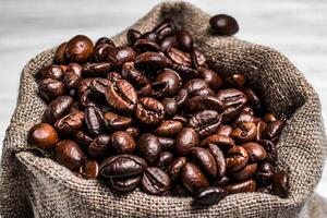 Brown roasted coffee beans in the sackon the blurred background. The bag full of fresh coffee grains. Close-up photo