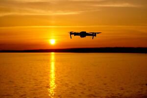 zumbido volador a el puesta de sol momento. zumbido quadcopter con digital cámara volador a puesta de sol foto