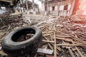 Old broken empty abandoned industrial building interior at night. Old tire and planks. photo