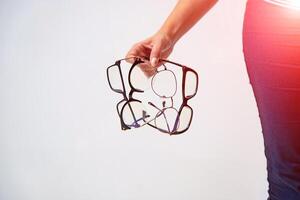 Spectacles closeup. Woman hand holds black framed eyeglasses. Four pairs of modern glasses. photo