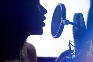 Close-up of girl in headphones singing a song. Professional recording studio photo