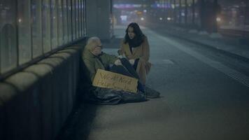 Kind Woman Helping Sad Elderly Homeless Man Outside In Cold Night video