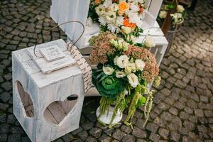 Horizontal image of rustic wedding decorations. Wooden boxes standing on the floor, decorated by white flowers and greenery. photo