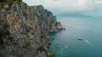 scogliere su sponde di capri con Barche su calma mare acque. aspro costa di italiano isola nel estate giorno. aereo Visualizza di natura paesaggio. video