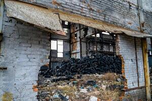 A bunch of car tires are in an abandoned factory. View of old factory inside. Close-up photo