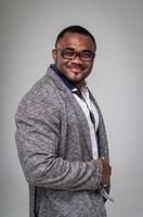 Cheerful good looking man in glasses standing. African american businessman in stylish grey coat posing. photo