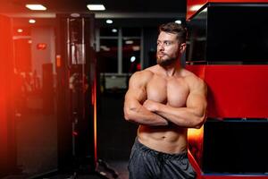 Strong man with muscular body type training and posing in modern sports hall. photo