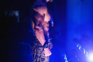 Handsome man with big muscles, posing at the camera in the gym, Black and blue background. Portrait of a bodybuilder with naked torso. Closeup. photo