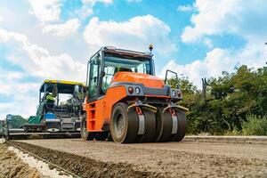 machine for ramming the ground and steamroller for asphalt run through the road in the summer photo