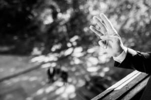 Man hand showing three fingers. Black and white photo, focus point on hands. Blurred background. photo