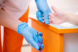 Nurse collects blood specimen from a finger. photo