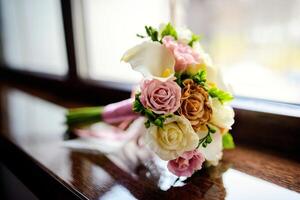 Gorgeous tender wedding bouquet with cream, ivory and pink roses on a windowsill. Closeup photo