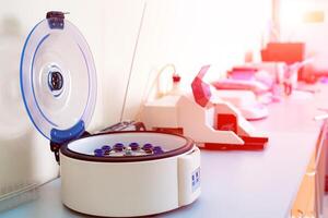 Female scientist loads some vials of liquid into a centrifuge in a laboratory photo