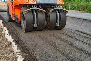 Roller machine works on asphalt. Close up view of the road roller working on the new road construction site photo