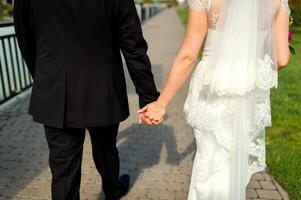 Wedding theme, holding hands newlyweds. Walking together. Groom and bride. photo