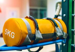 Yellow punching bag of five kilograms on a stand in a gym. Training equipment for sport. Close-up photo