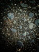 A collection of rocks scattered on the ground, varying in size, shape, color, and texture. photo