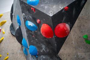 Red and blue grips on black artificial wall climbing in sports center photo