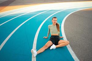 Tired happy woman runner taking rest after run sitting running track photo