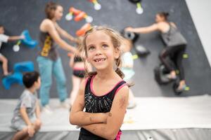 Cute little girl climber standing arms crossed in sports center photo