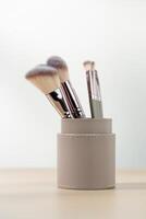 Various sizes of Rouge Brushes in pastel pink cup on a wooden table photo