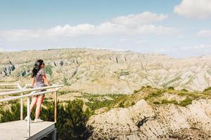 Brunette woman stands on the platform viewpoint and looks over beautiful landscape of Vashlovani nature reserve photo