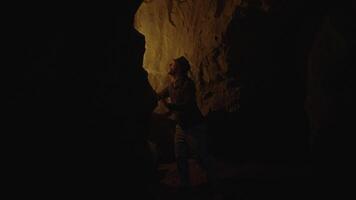 homem segurando uma queimando luz da tocha explorando floresta caverna panorama dentro Sombrio noite video