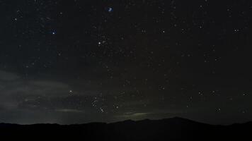 Timelapse av rör på sig stjärnor och moln över de bergen i natt himmel. 4k video